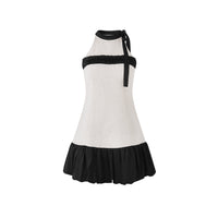 A sleeveless halter-neck dress with a textured off-white body, black ruffled trim across the bust, and a black ruffled hem, shown against a plain white background.